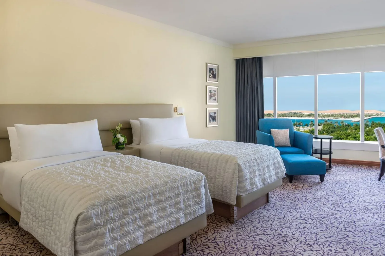 Le Royal Meridien Abu Dhabi – hôtel à Abu Dhabi, United Arab Emirates – une chambre d'hôtel avec deux lits et une chaise bleue au Le Royal Meridien Abu Dhabi à Abu Dhabi