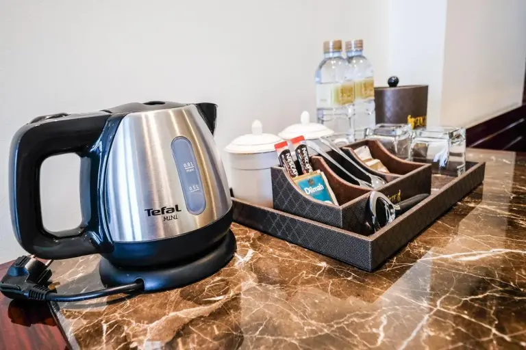 Zona de té y café en la habitación en LK Grand Empire en Pattaya con hervidor, tazas y agua embotellada
