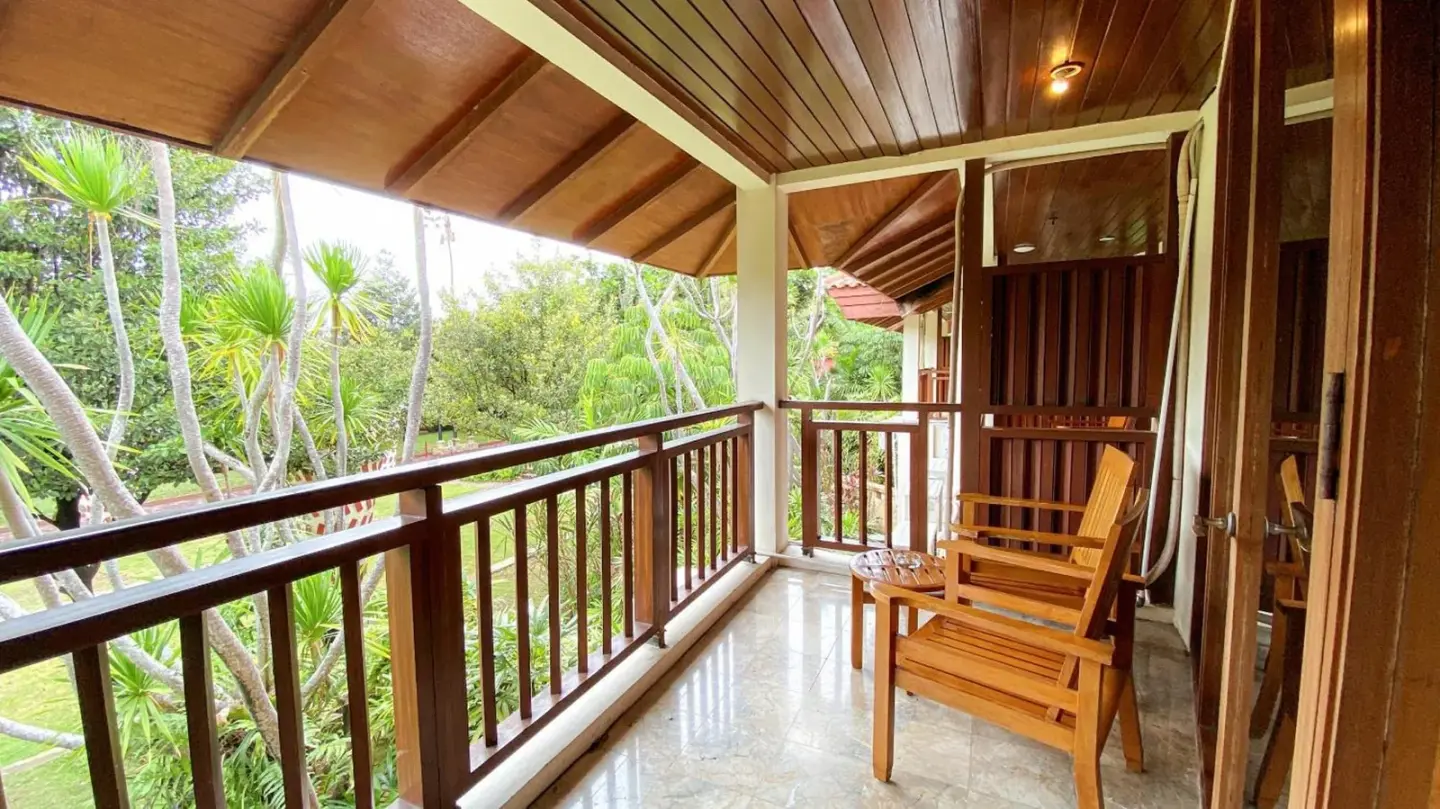 Balkon im Lorin Solo Hotel mit Holzstühlen und üppigem Gartenblick in Surakarta