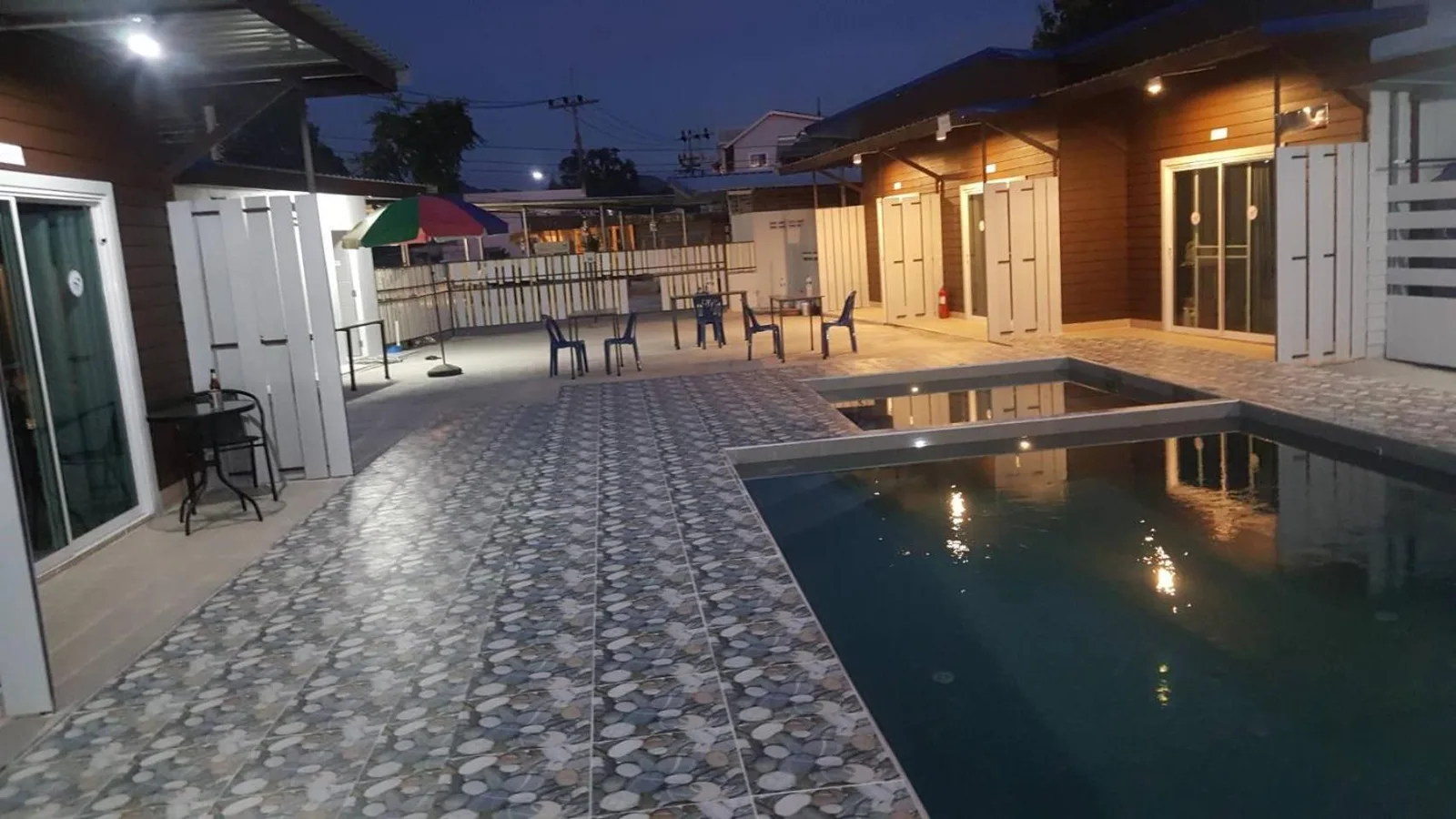 Poolhof bei Nacht im Lovely Paradise Phangan Hotel auf Ko Pha-Ngan mit gefliesten Wegen und Zimmergebäuden.