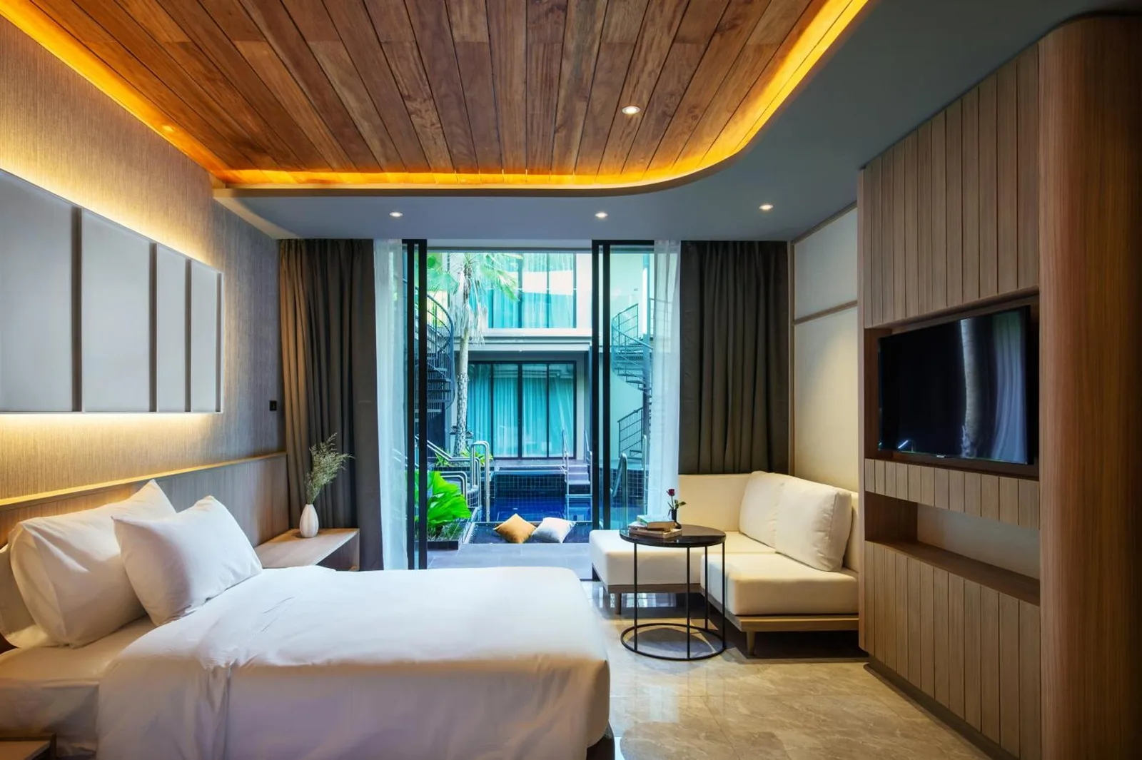 Chambre donnant sur la cour au Luminous Resort & Spa by Areca à Phuket avec lit, canapé et mur TV