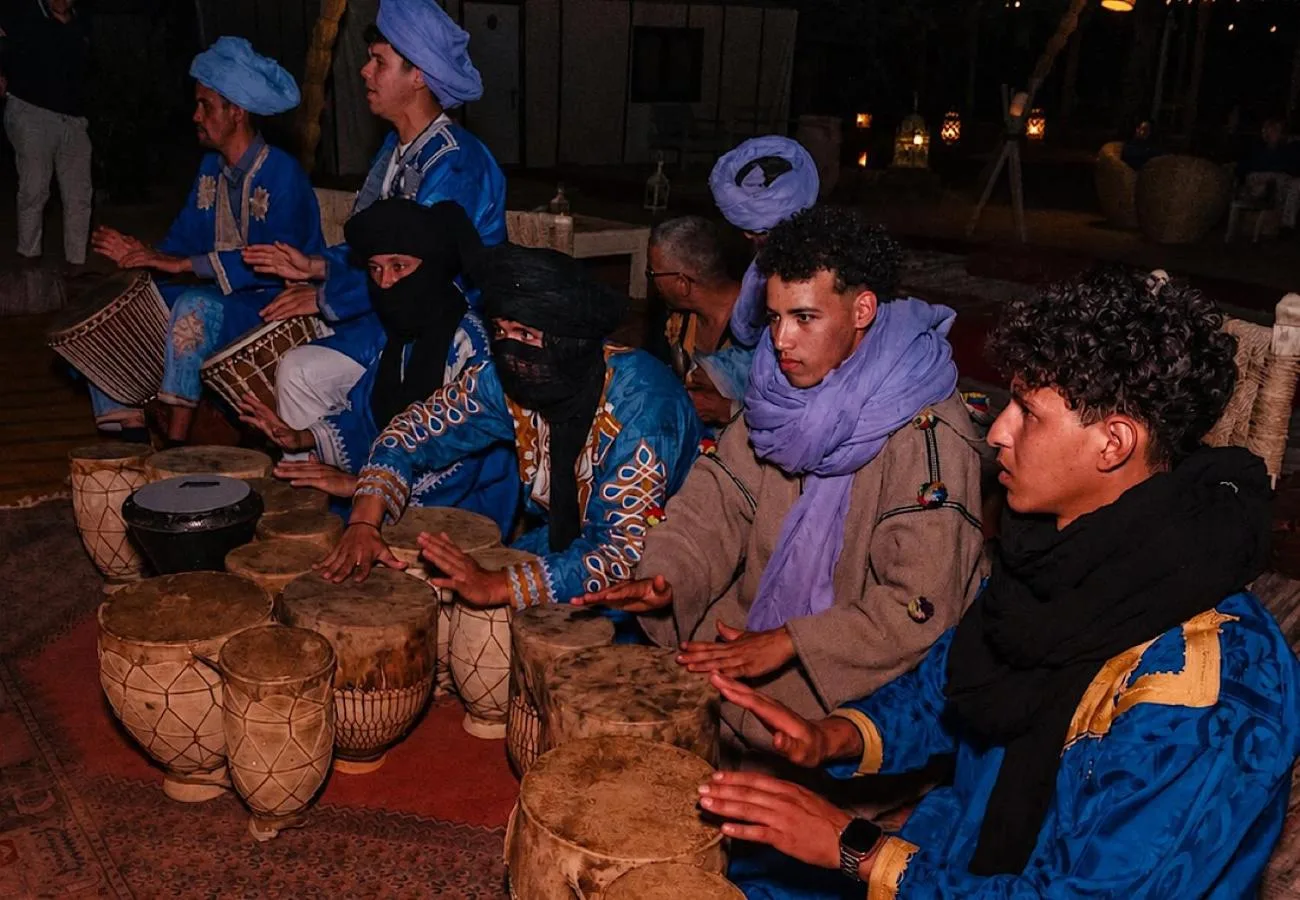 Luna Desert Luxury Camp – Merzouga, Morocco hotel – a group of people sitting around a table with baskets at Luna Desert Luxury Camp in Merzouga