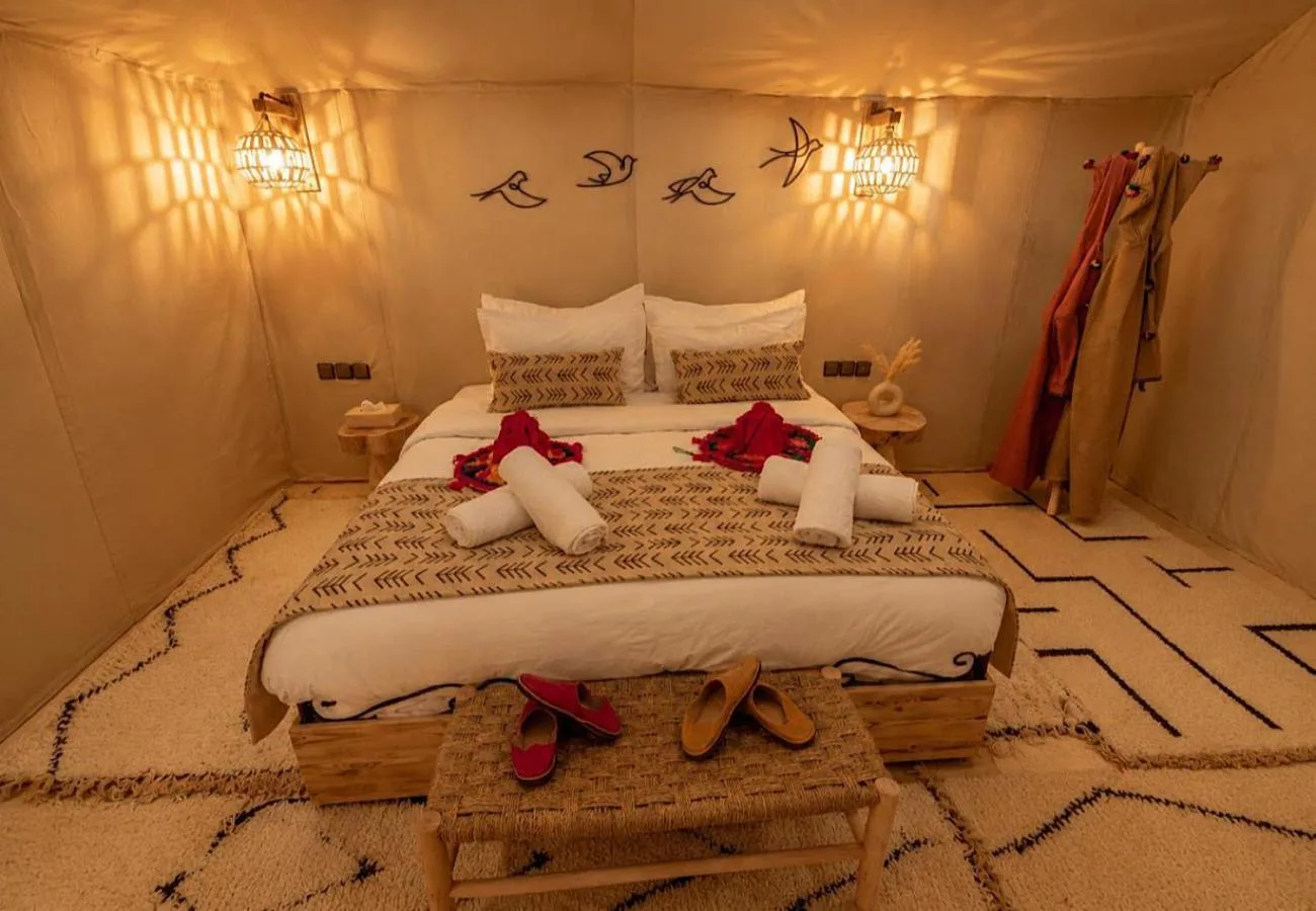 Double room at Luna Desert Luxury Camp in Merzouga with a large bed, towels, and desert-style decor