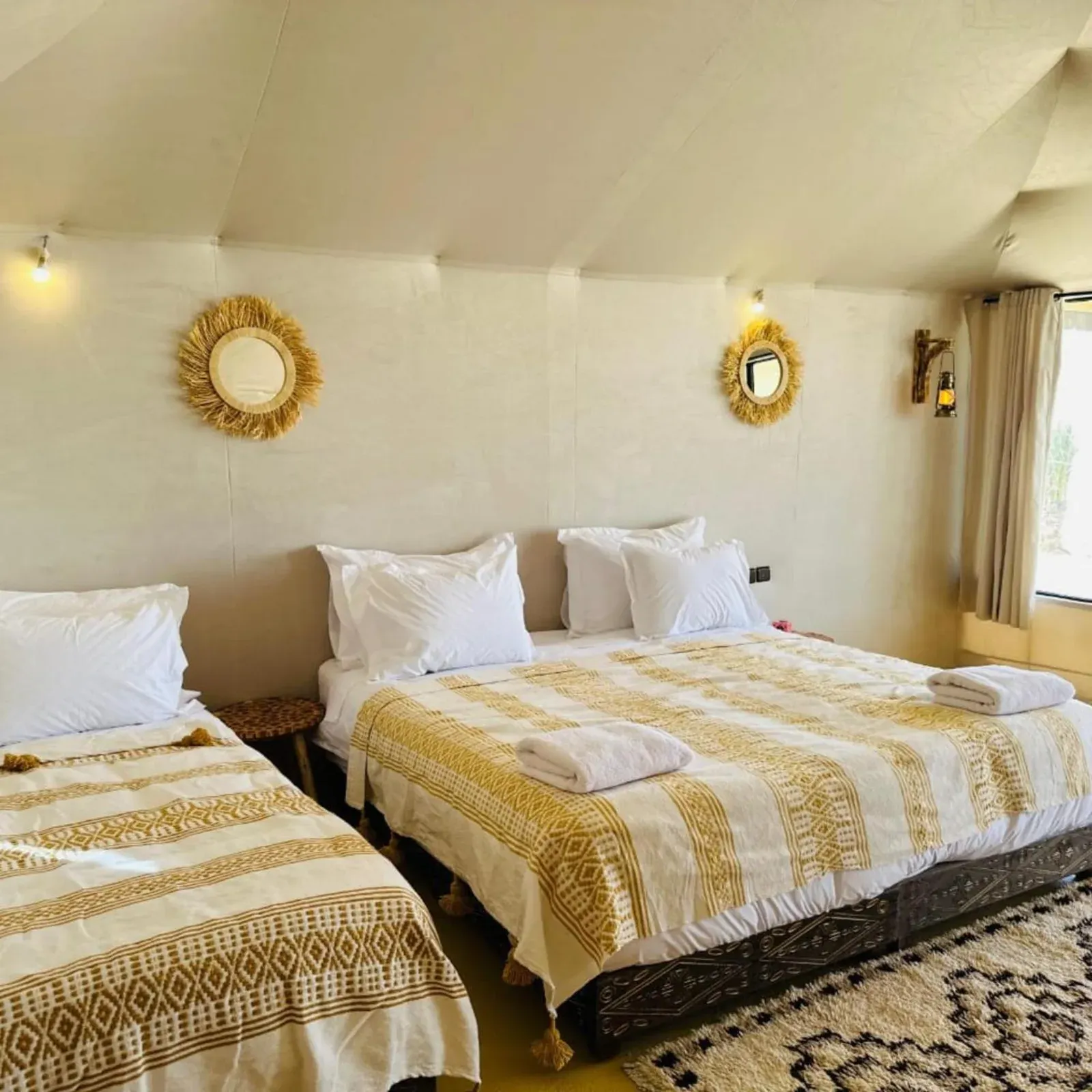 Family room at Luna Desert Luxury Camp in Merzouga with multiple beds and bright cream interior