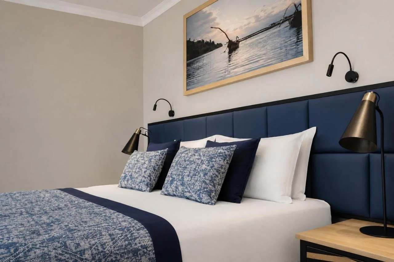 Interior of a deluxe room at LUX* Lake Kivu featuring a cozy bed and artistic decor.
