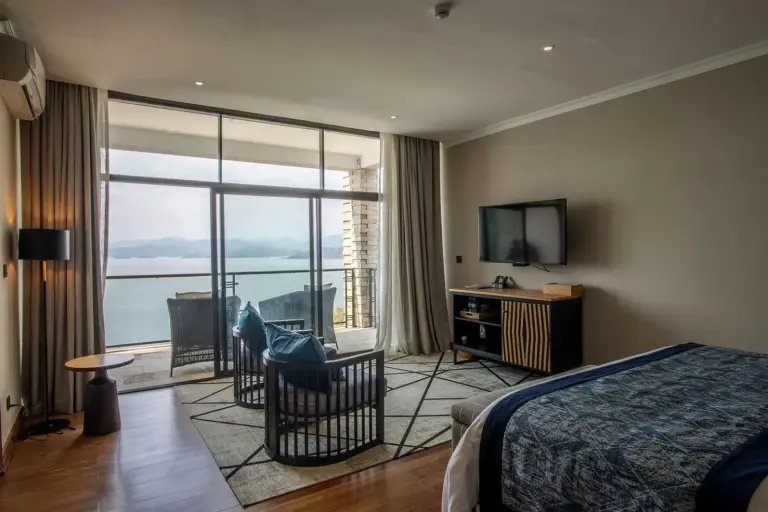 Ein geräumiges Zimmer im LUX* Lake Kivu mit atemberaubendem Blick auf den See durch große Fenster.