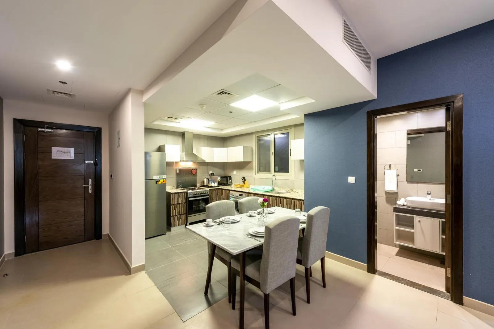 Essbereich und kompakte Küche im Luxe Grand Hotel Apartments in Schardscha mit modernen Geräten und Zugang zum Badezimmer.