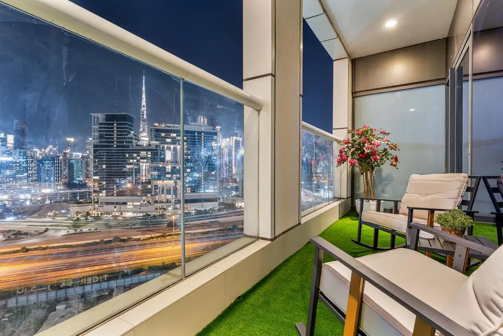 Luxury 1BR balcony overlooking the city skyline with seating area.