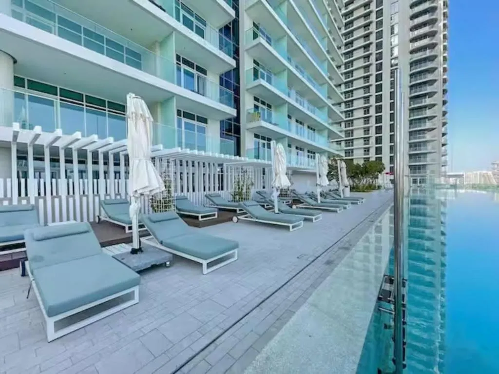 Sillas de salón junto a la piscina en el Apartamento de lujo frente a la playa con vista a la marina en Dubái