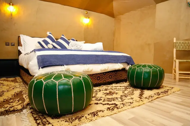 Luxury berber style in Merzouga twin bedroom with blue striped bedding and green poufs