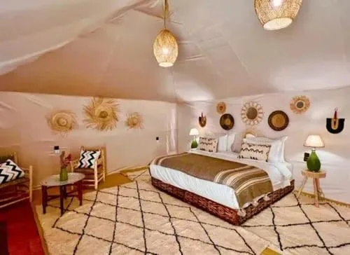 Luxury Camp Plus Activities in Merzouga spacious tent bedroom with decorative wall art