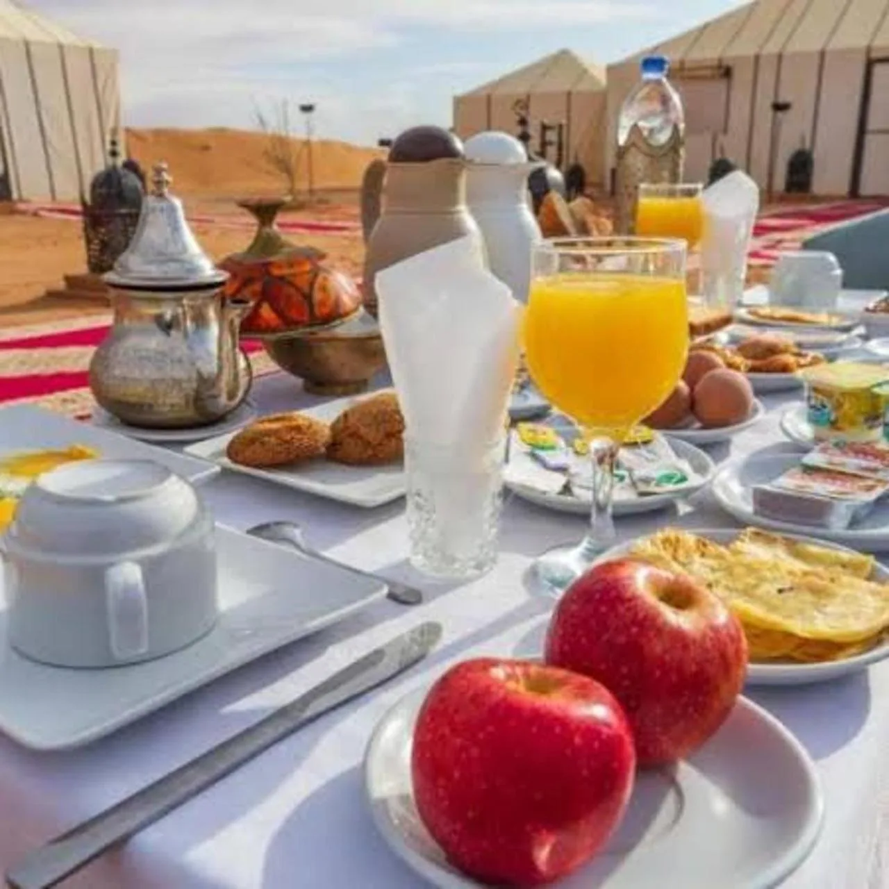 Breakfast setup at Luxury Camp View in Merzouga with fruit, juice, tea, and pastries