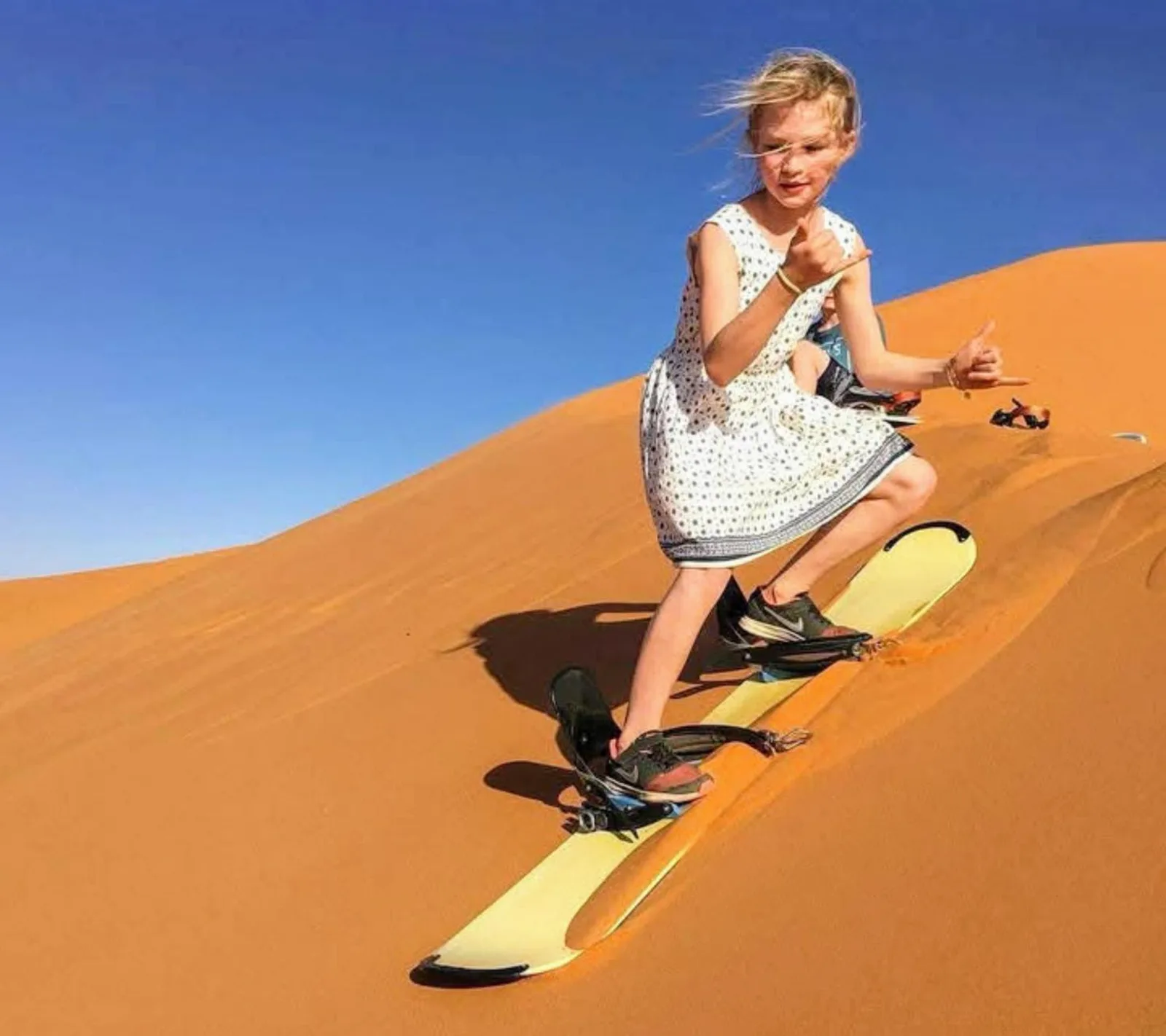 Niño practicando sandboard en el desierto de Merzouga