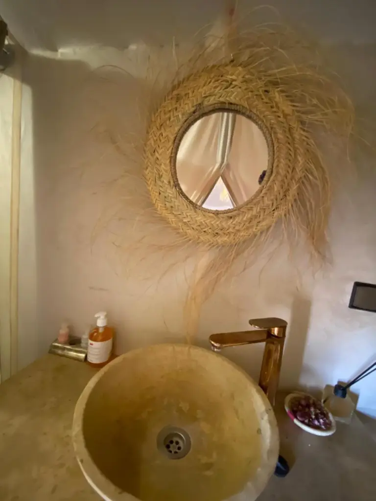 Lavabo et miroir élégants dans la salle de bains au Luxury Merzouga Stars Camp à Merzouga avec décoration naturelle tressée.