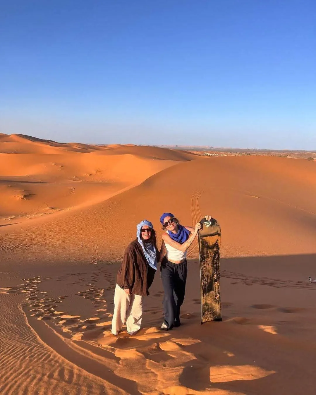 Gäste stehen auf den Dünen nahe dem Magnifique Luxury Camp in Merzouga, Marokko, mit weitem Blick über die Sahara.