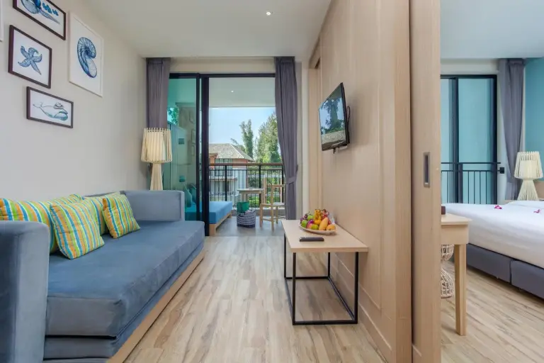 Family suite living area at Mai Khaolak Beach Resort & Spa - TUIBLUE Mai Khaolak with sofa, TV, and balcony.