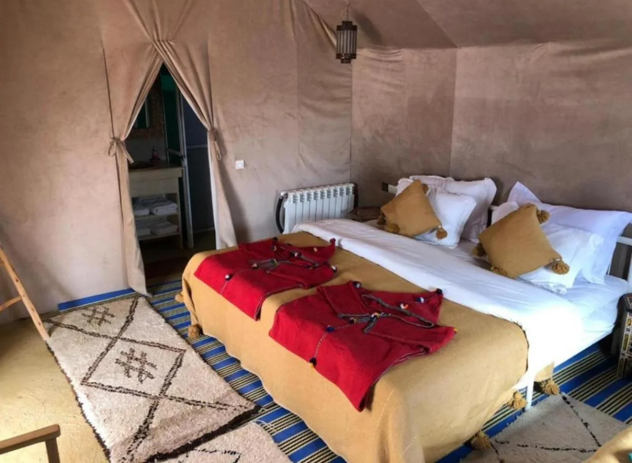 Majestic Dunes Luxury Camp – hotel en Merzouga, Marruecos – un dormitorio con una cama grande en una tienda en Majestic Dunes Luxury Camp en Merzouga