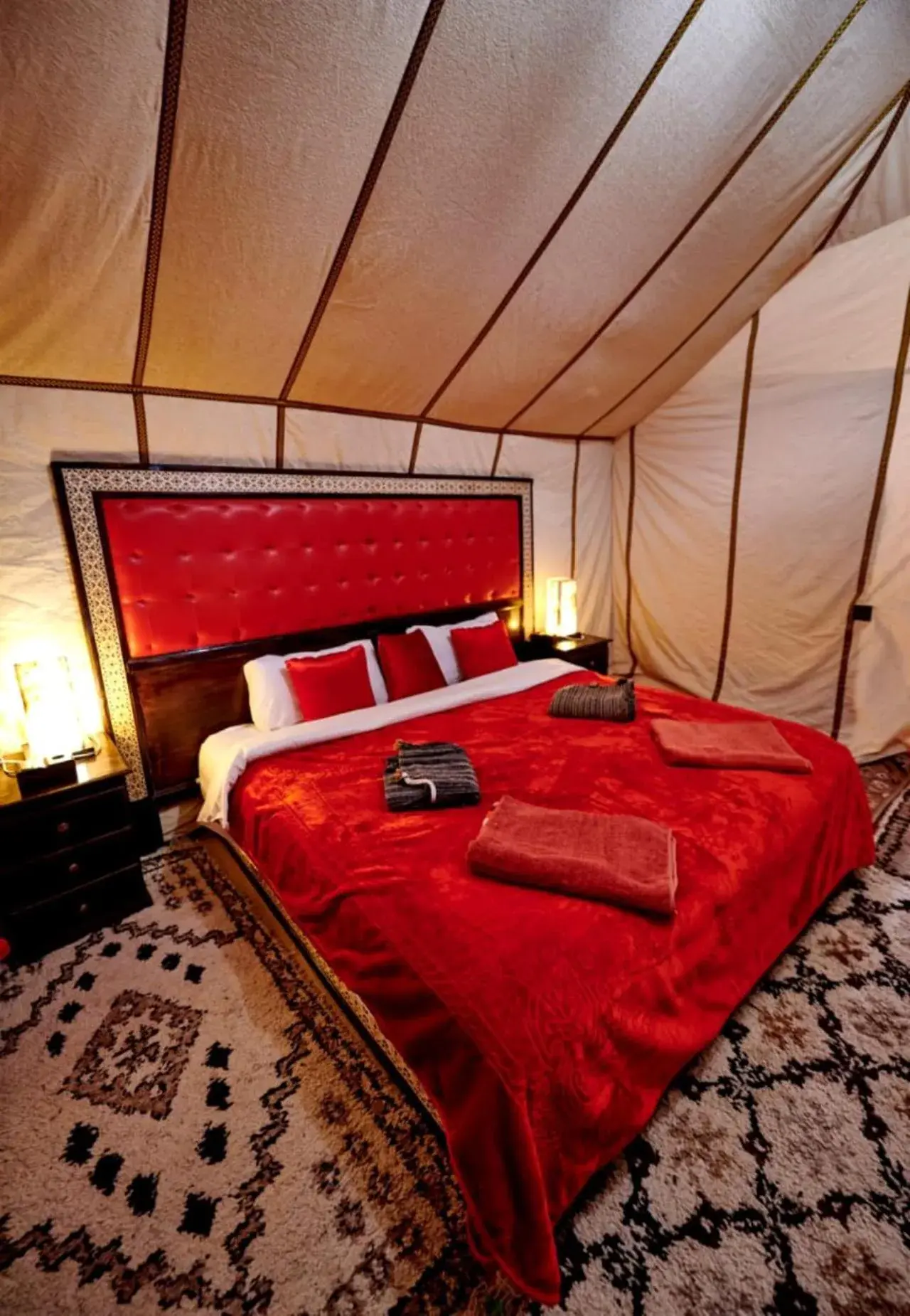 Majestic Dunes Luxury Camp – hotel en Merzouga, Marruecos – un dormitorio con una cama roja en una tienda en Majestic Dunes Luxury Camp en Merzouga