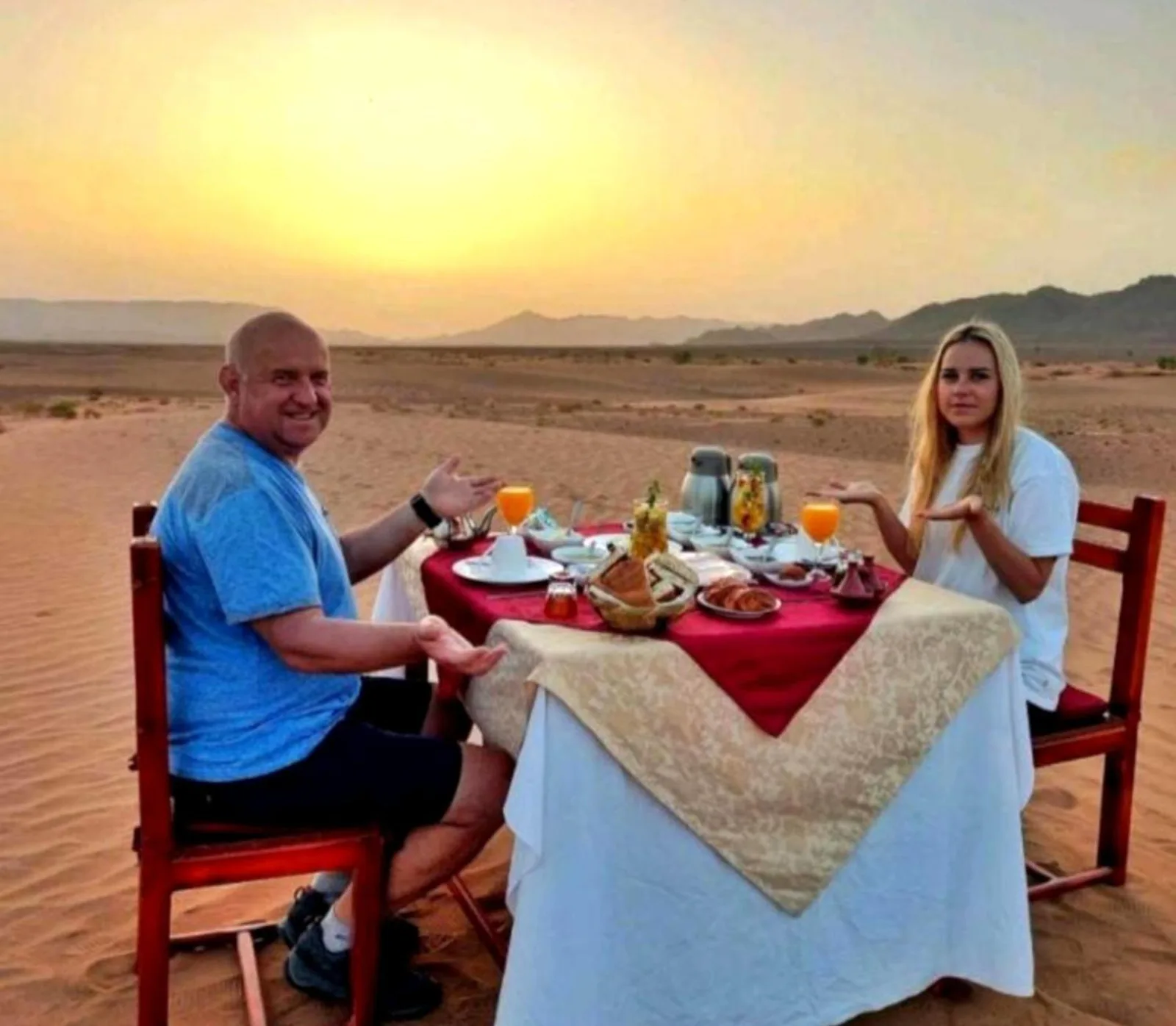 Majestic Dunes Luxury Camp – hotel en Merzouga, Marruecos – un hombre y una mujer sentados en una mesa en el desierto en Majestic Dunes Luxury Camp en Merzouga