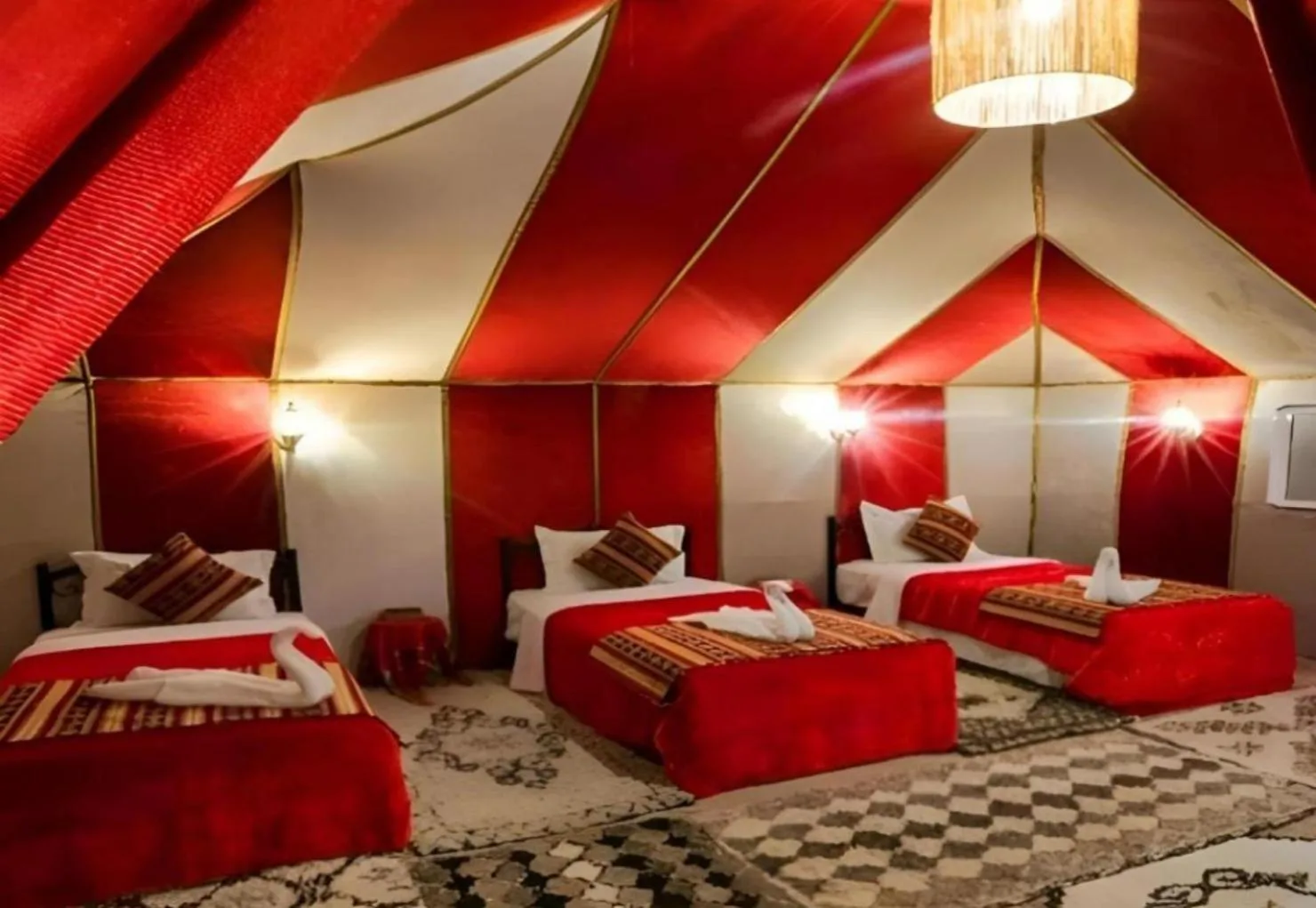 Majestic Dunes Luxury Camp – hotel en Merzouga, Marruecos – una habitación con tres camas en una tienda roja y blanca en Majestic Dunes Luxury Camp en Merzouga