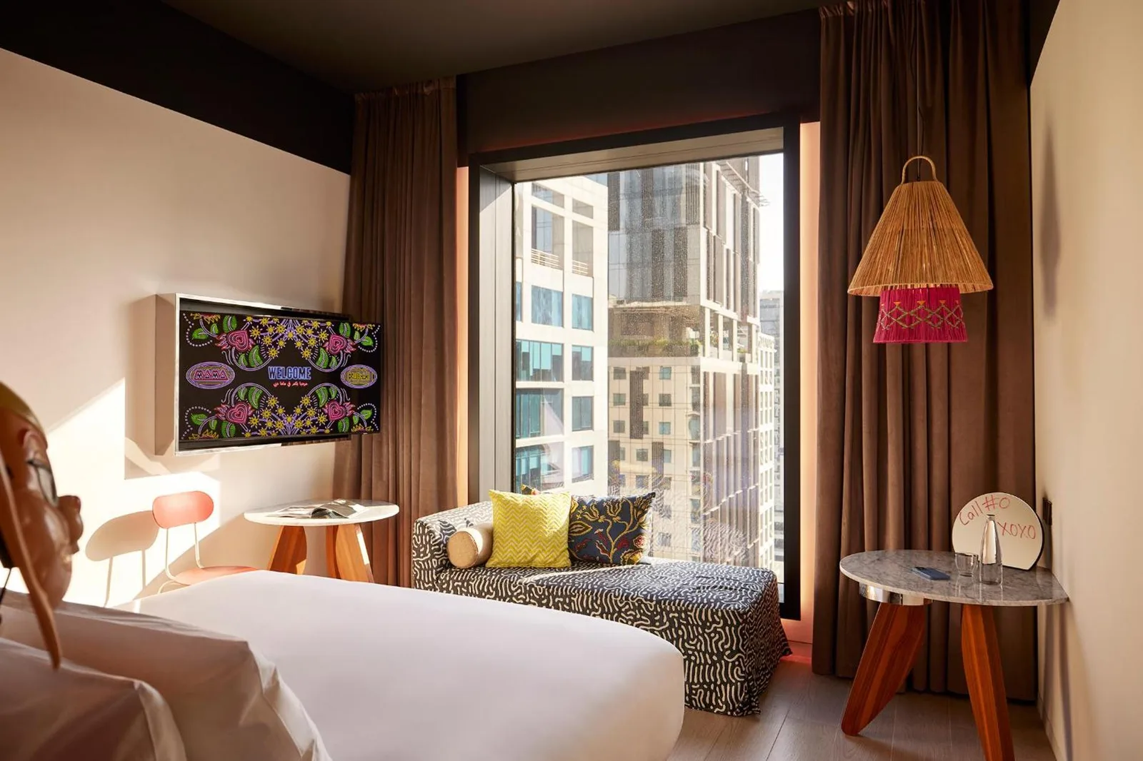 Mama Shelter Dubai room with a window seat, bed, and city view