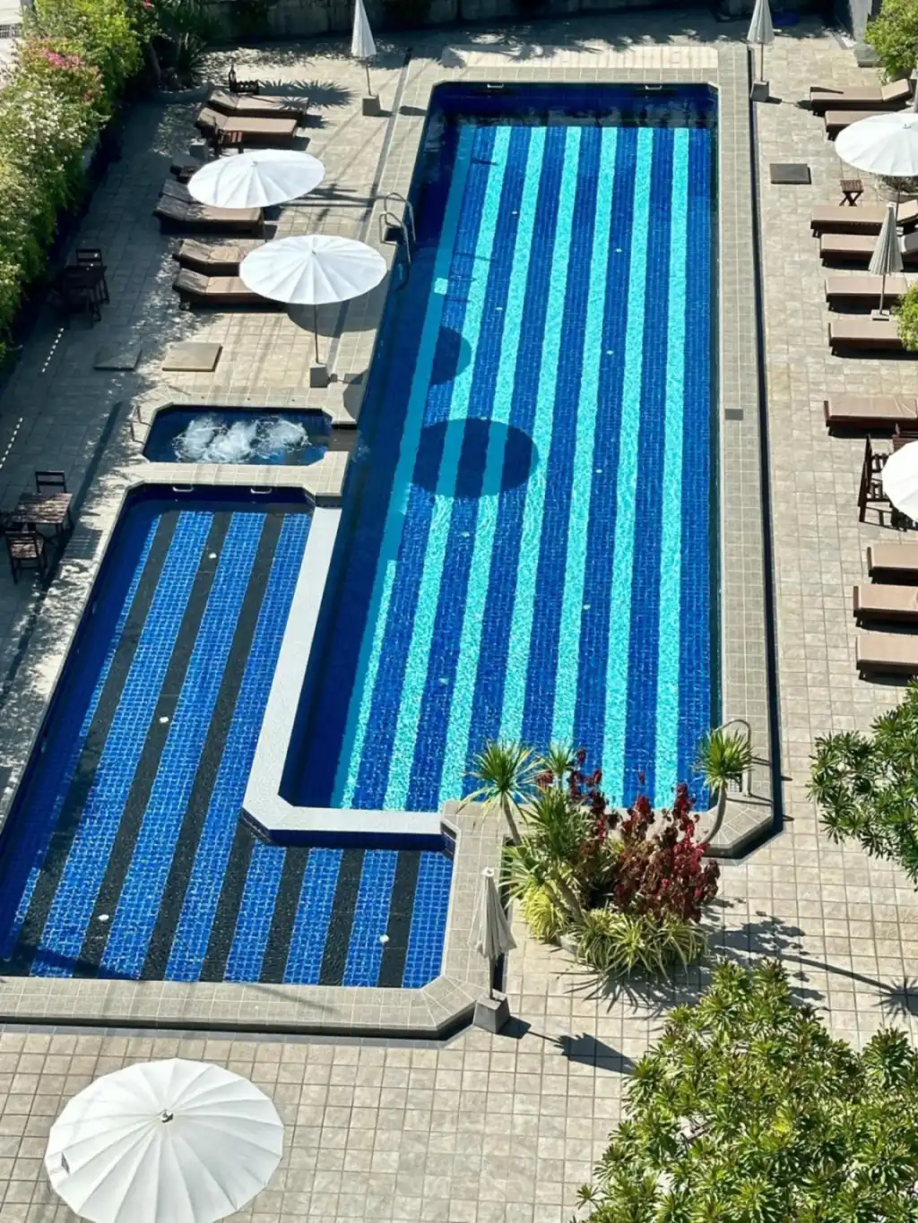 Swimming pool area at Mangrove Prestige Hotel in Pattaya with blue tiled pools and sun loungers