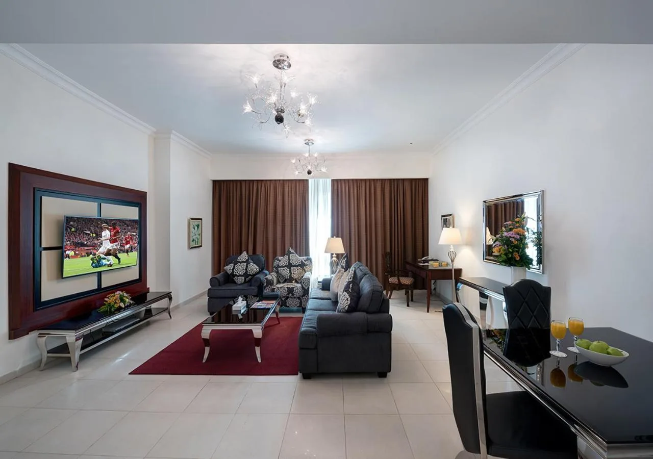 Marina Hotel Apartments Dubai apartment lounge with sofa seating, TV, desk, and dining corner