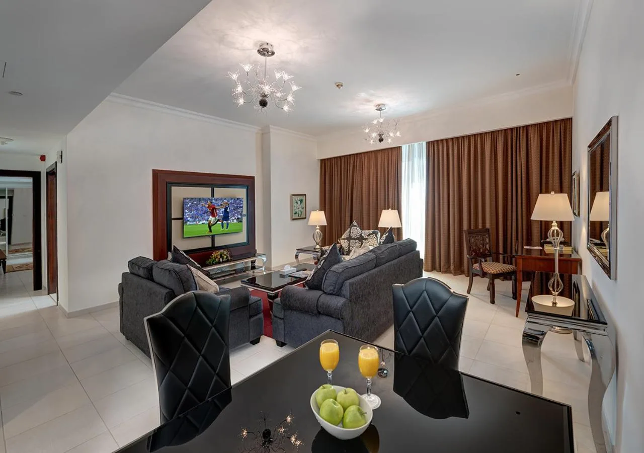 Marina Hotel Apartments Dubai apartment dining and living area with sofa seating and a black dining table