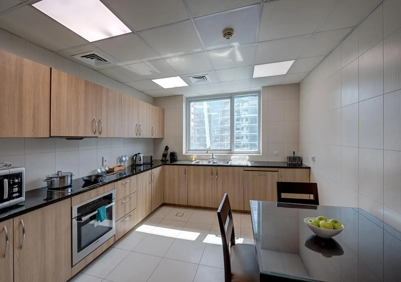 Marina Hotel Apartments Dubai modern kitchen interior with L-shaped counters, stove, and window