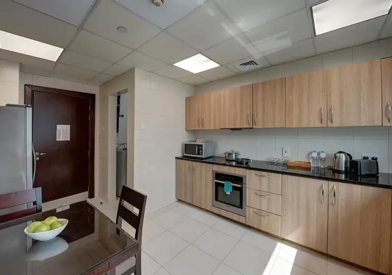 Marina Hotel Apartments Dubai fully equipped kitchen with cabinets, oven, microwave, and dining table