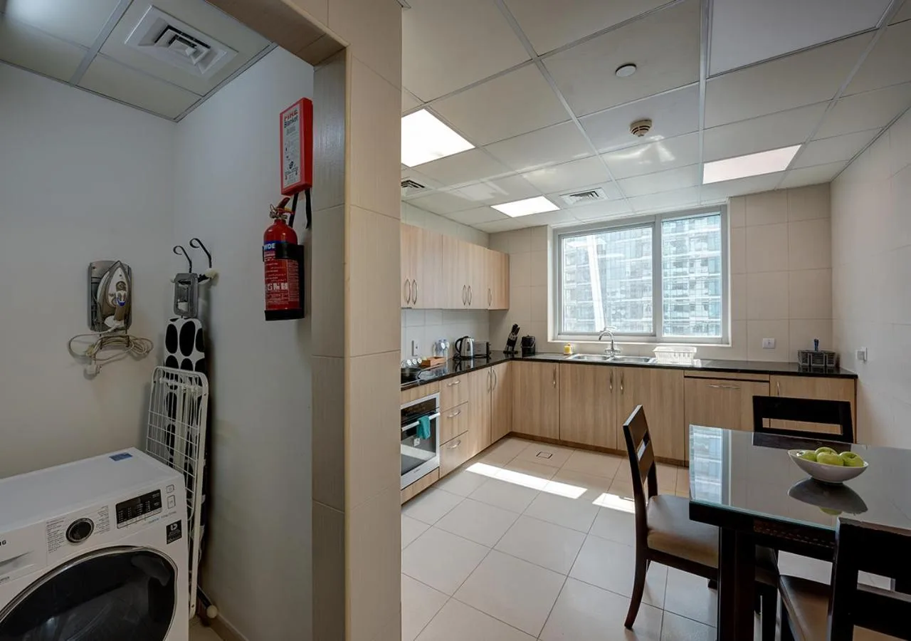 Marina Hotel Apartments Dubai utility area with washing machine beside a large apartment kitchen