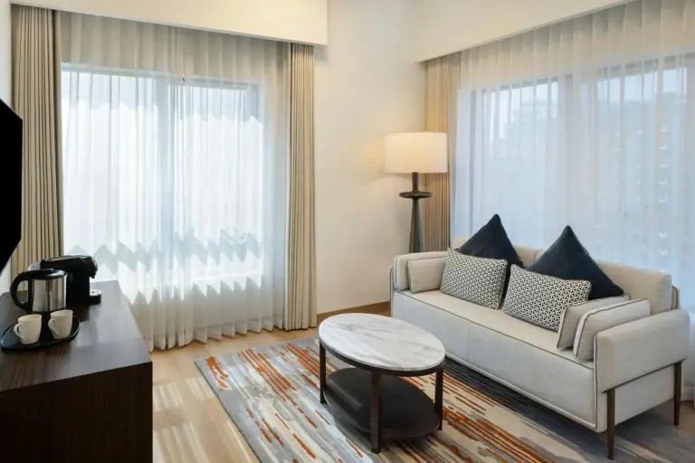 Eleganter Wohnbereich im Marriott Hotel Production City, Dubai mit Sofa, Couchtisch und großen Fenstern