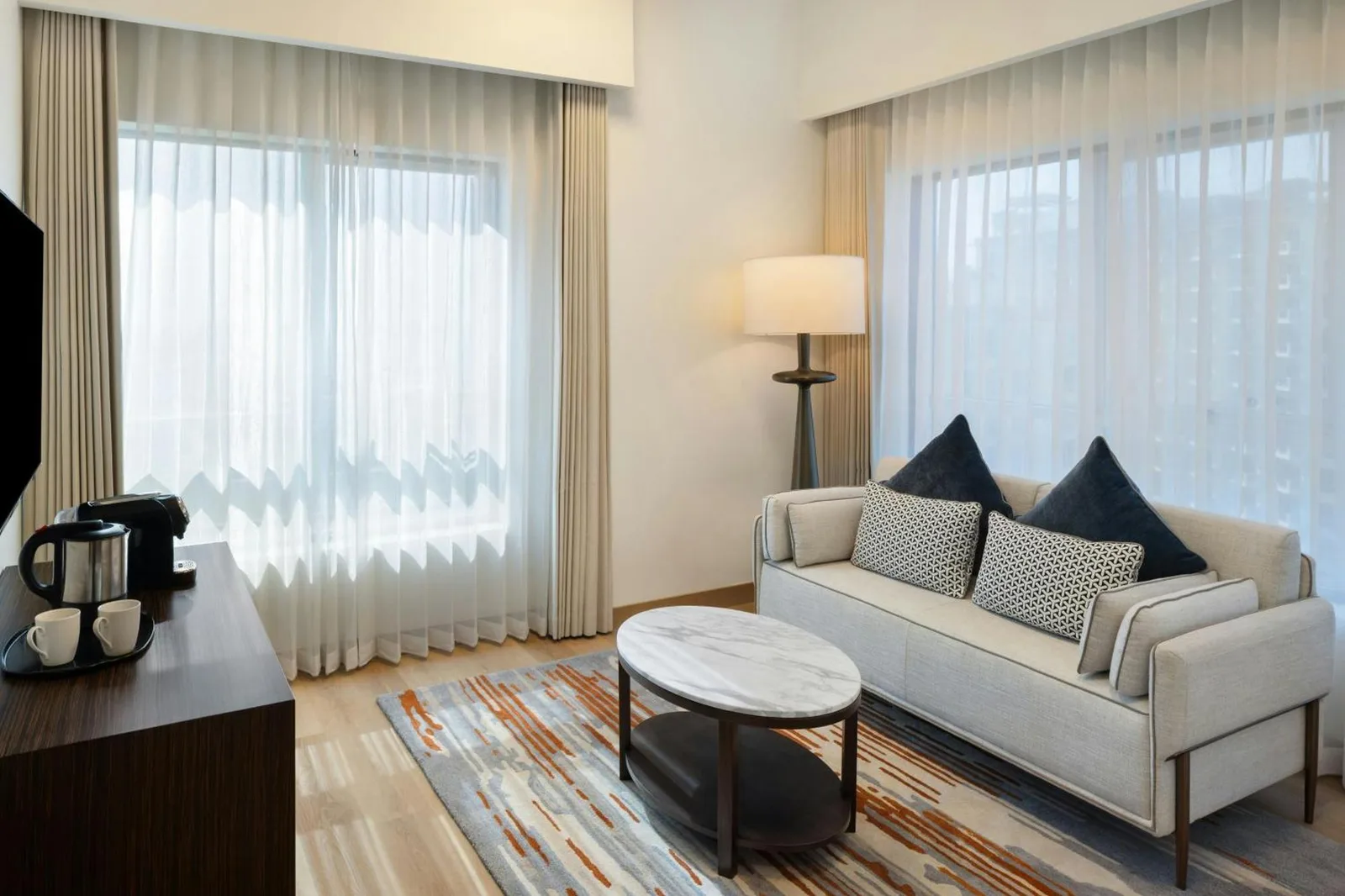Eleganter Wohnbereich im Marriott Hotel Production City, Dubai mit Sofa, Couchtisch und großen Fenstern