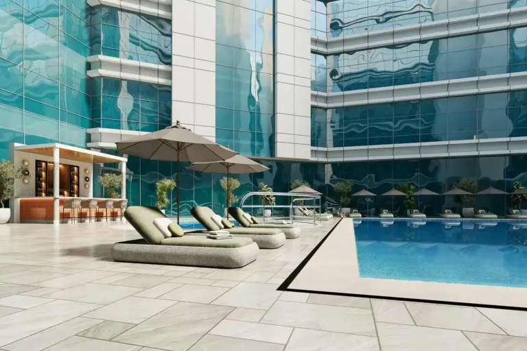 Außenpool im Marriott Hotel Production City, Dubai mit Liegestühlen und moderner Glasfassade