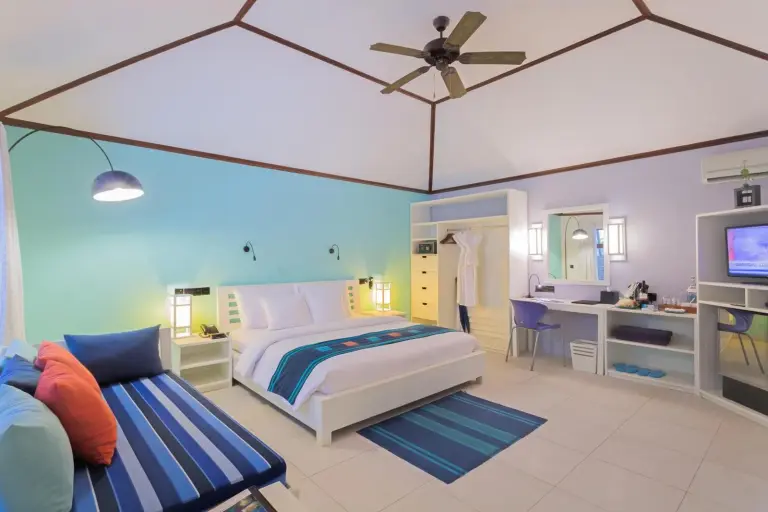 Innenansicht eines Deluxe-Zimmers im Meeru Maldives Resort mit lebendigen Farben