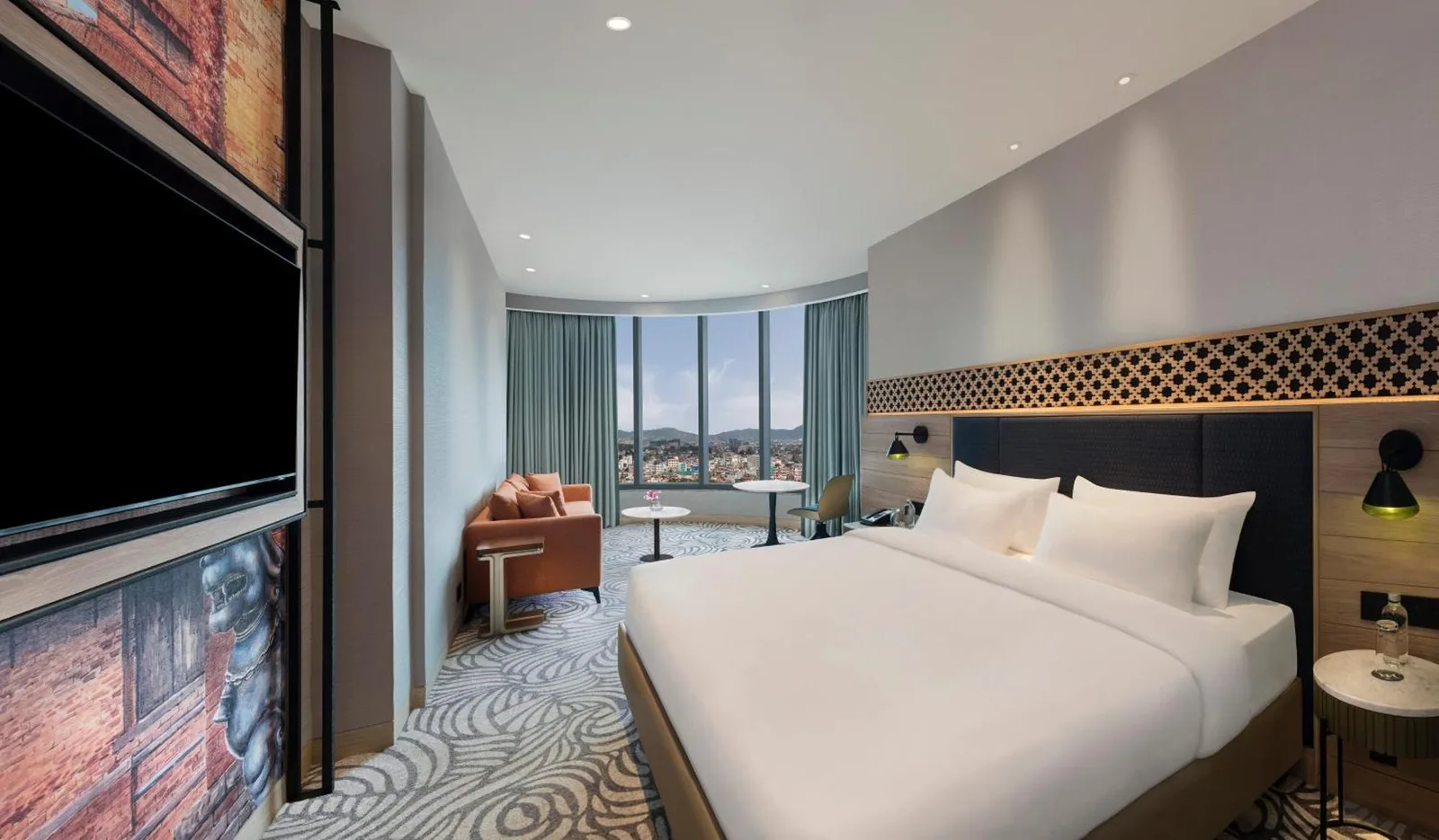 Deluxe room at Mercure Kathmandu Sukedhara Heights with bed, lounge seating, and city view window