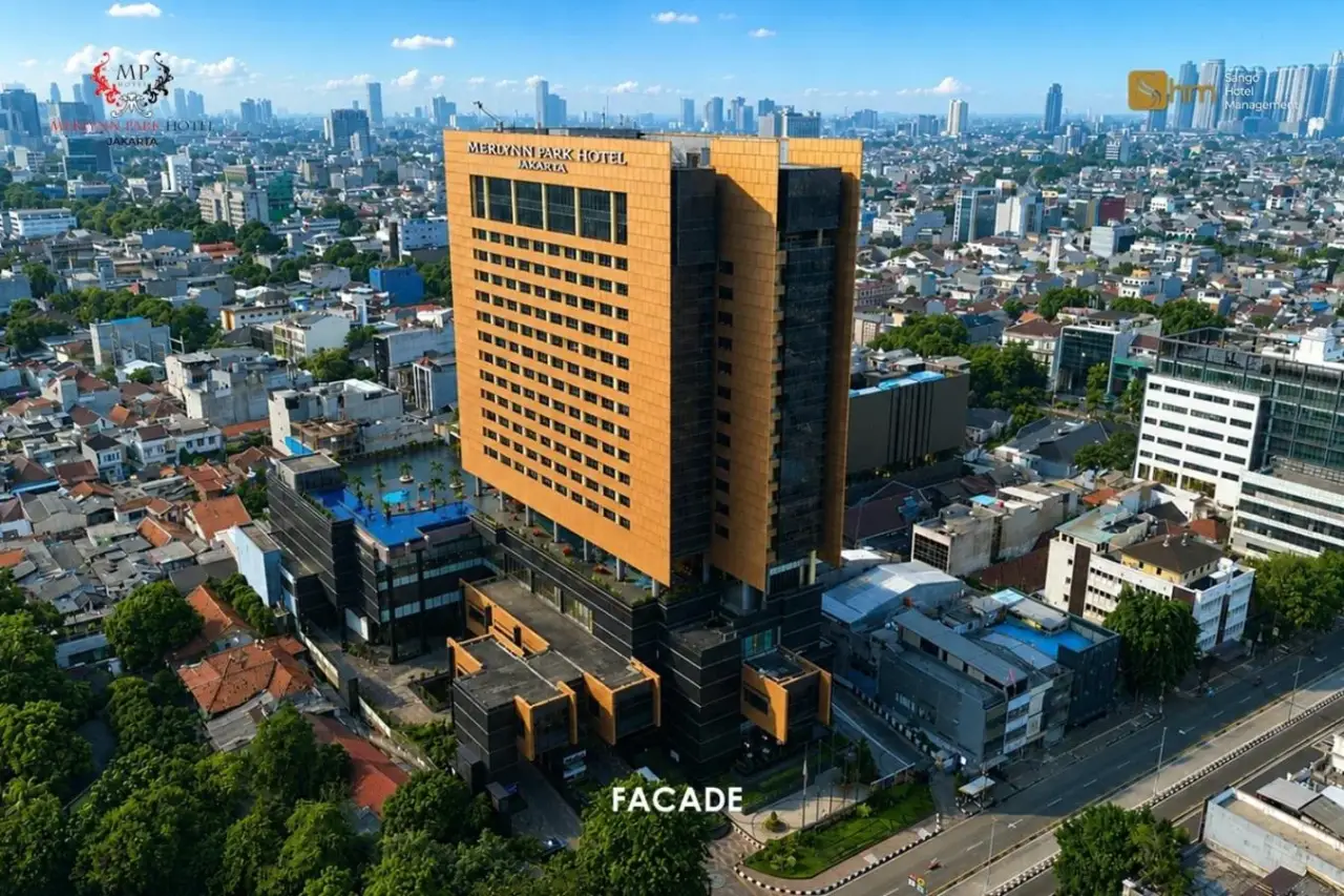 Luftaufnahme der Außenansicht des Merlynn Park Hotel Jakarta mit Hochhausfassade und Stadt-Skyline.