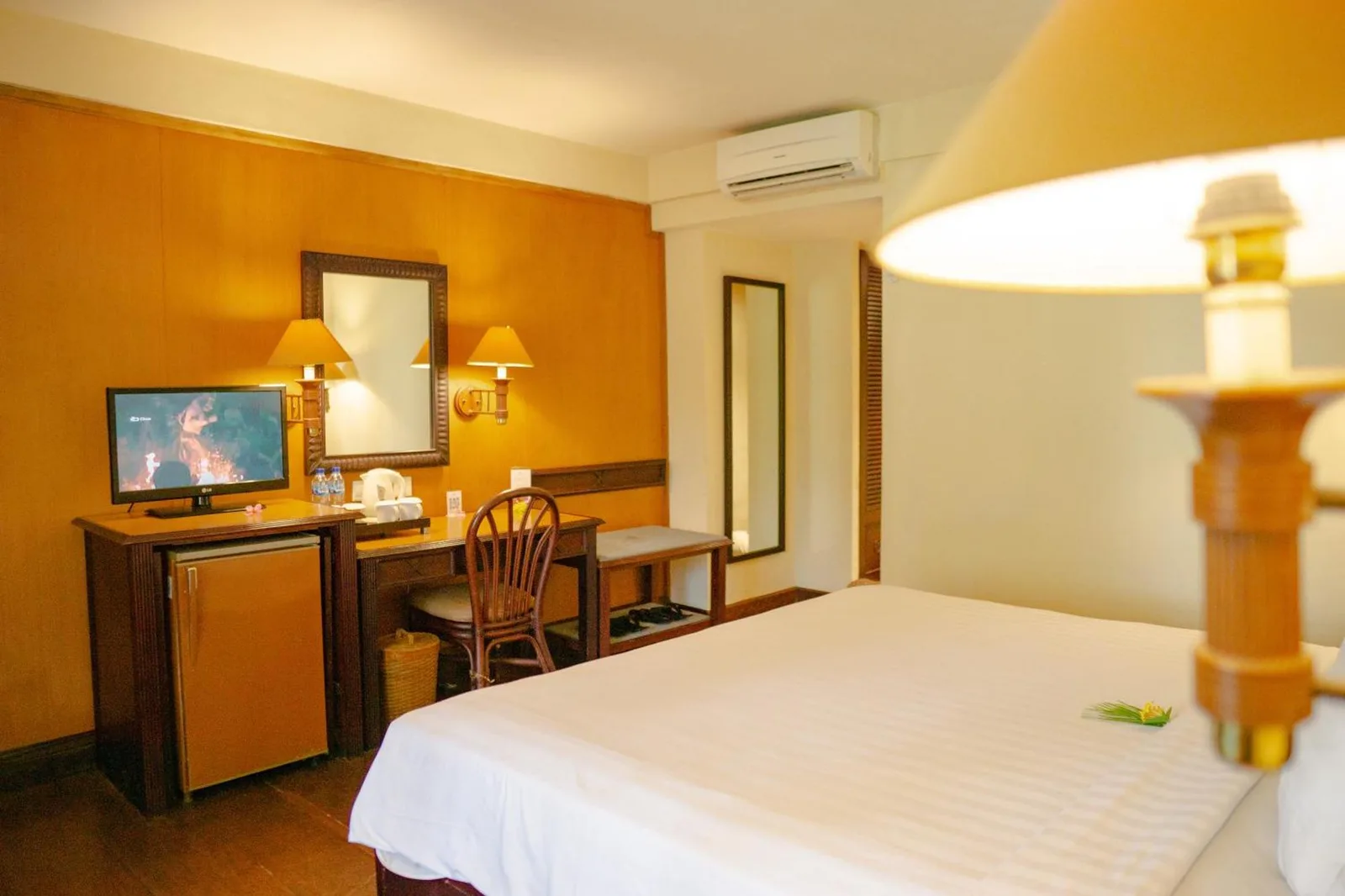 Interior del dormitorio en Merumatta Senggigi Lombok en Mataram con escritorio de trabajo, espejo y aire acondicionado