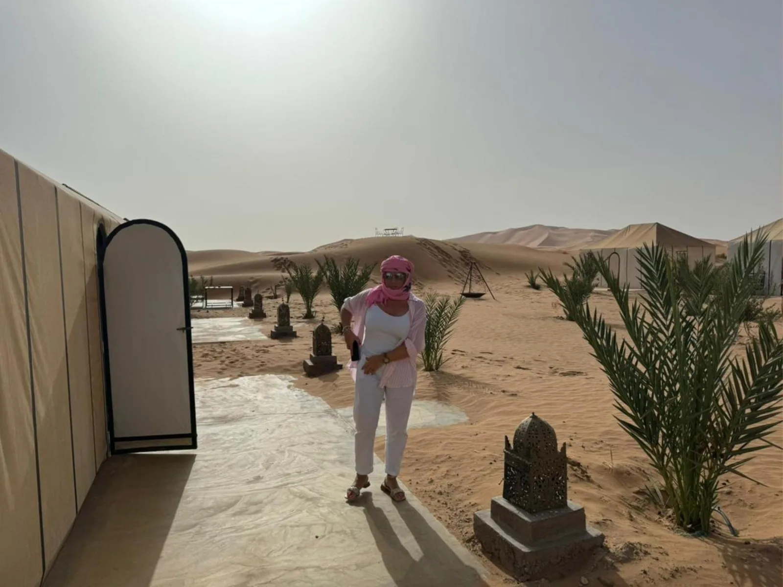 Merzouga Activities Camp outdoor walkway with guest and desert dunes in Merzouga