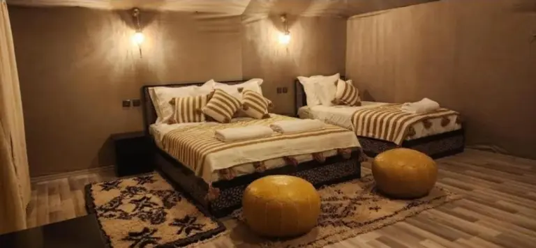Twin bed guest room at Merzouga Aicha Luxury Camp in Merzouga with warm lighting and modern decor.