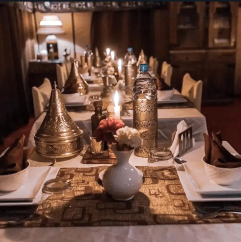 Merzouga Alicante Luxury Camp – hotel en Merzouga, Marruecos – una mesa larga con platos blancos y jarrones en Merzouga Alicante Luxury Camp en Merzouga