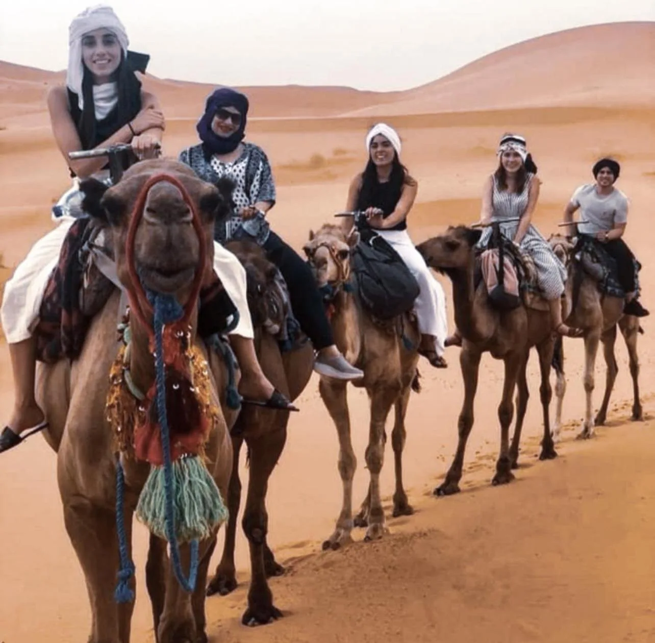 Huéspedes montando camellos en el Sahara cerca de Merzouga Alicante Luxury Camp en Merzouga