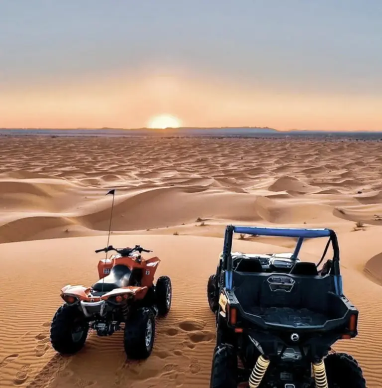 Vehículos ATV y buggy en las dunas cerca de Merzouga Alicante Luxury Camp en Merzouga al atardecer