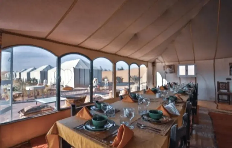 Interior de la tienda comedor en Merzouga Alicante Luxury Camp en Merzouga con mesas preparadas y ventanas arqueadas