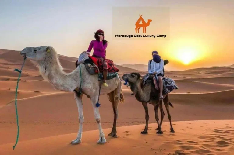 Turistas disfrutando de un paseo en camello durante el atardecer en Merzouga Cool Luxury Camp