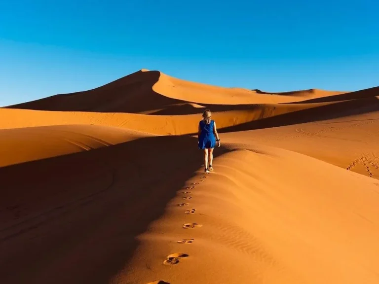 Huésped caminando sobre dunas de arena cerca de Merzouga Cool Luxury Camp