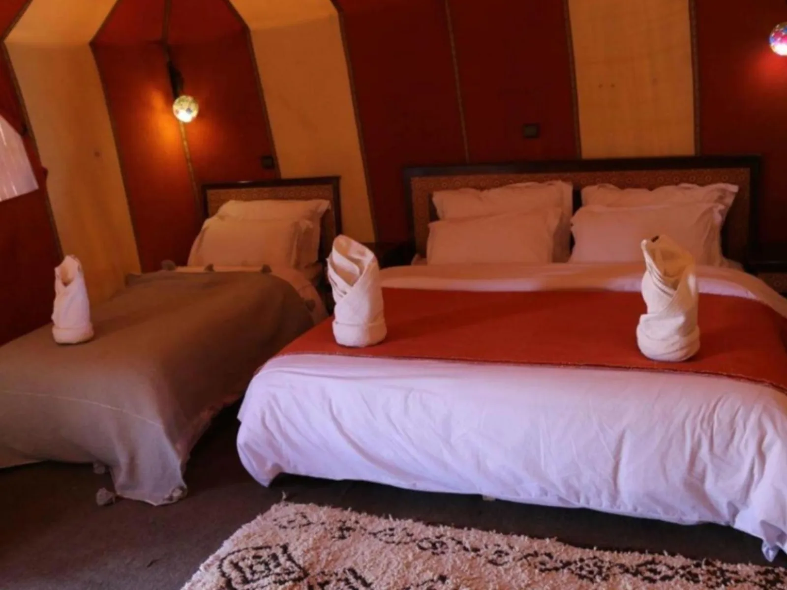 Habitación tienda doble en Merzouga DuneNova Luxury Camp en Merzouga con dos camas y paredes de la tienda en rojo anaranjado