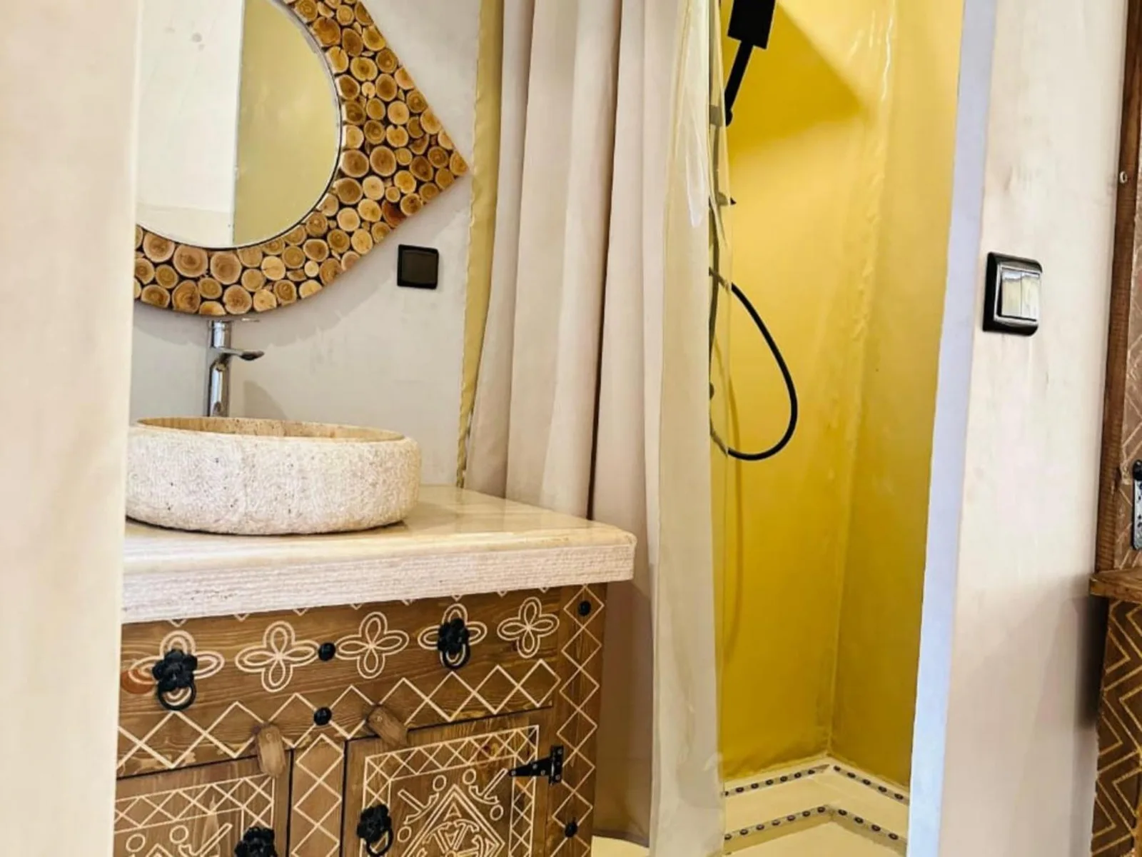 Zona de ducha y lavabo en Merzouga DuneNova Luxury Camp en Merzouga con espejo decorativo y espacio de ducha amarillo