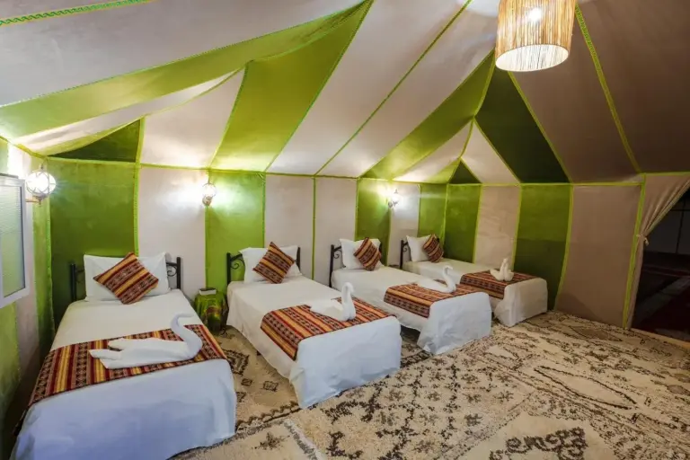 Habitación tienda doble en Merzouga DuneNova Luxury Camp en Merzouga con varias camas individuales y decoración tradicional del desierto