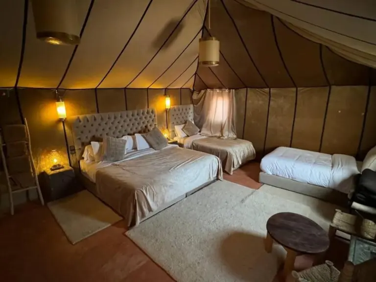Tienda comedor en Merzouga Eastern Camp Luxury en Merzouga con mesas y sillas preparadas bajo un dosel drapeado.